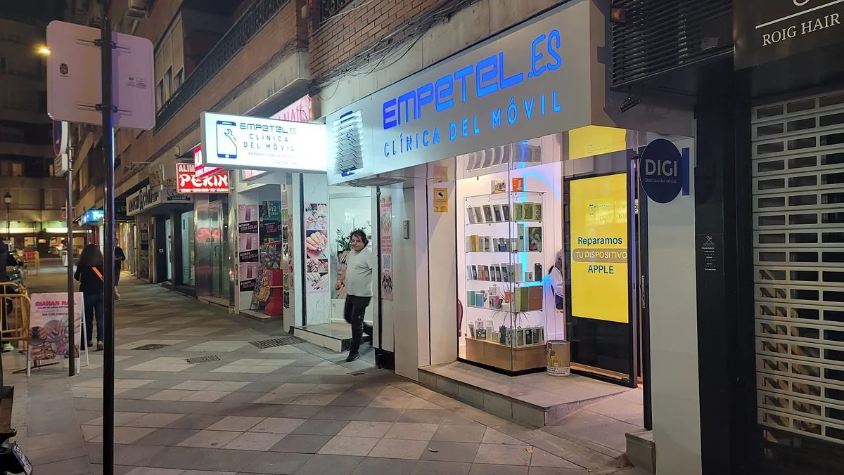 Fachada de Empetel de noche con el rótulo azul Empetel.es Clínica del Móvil encendido